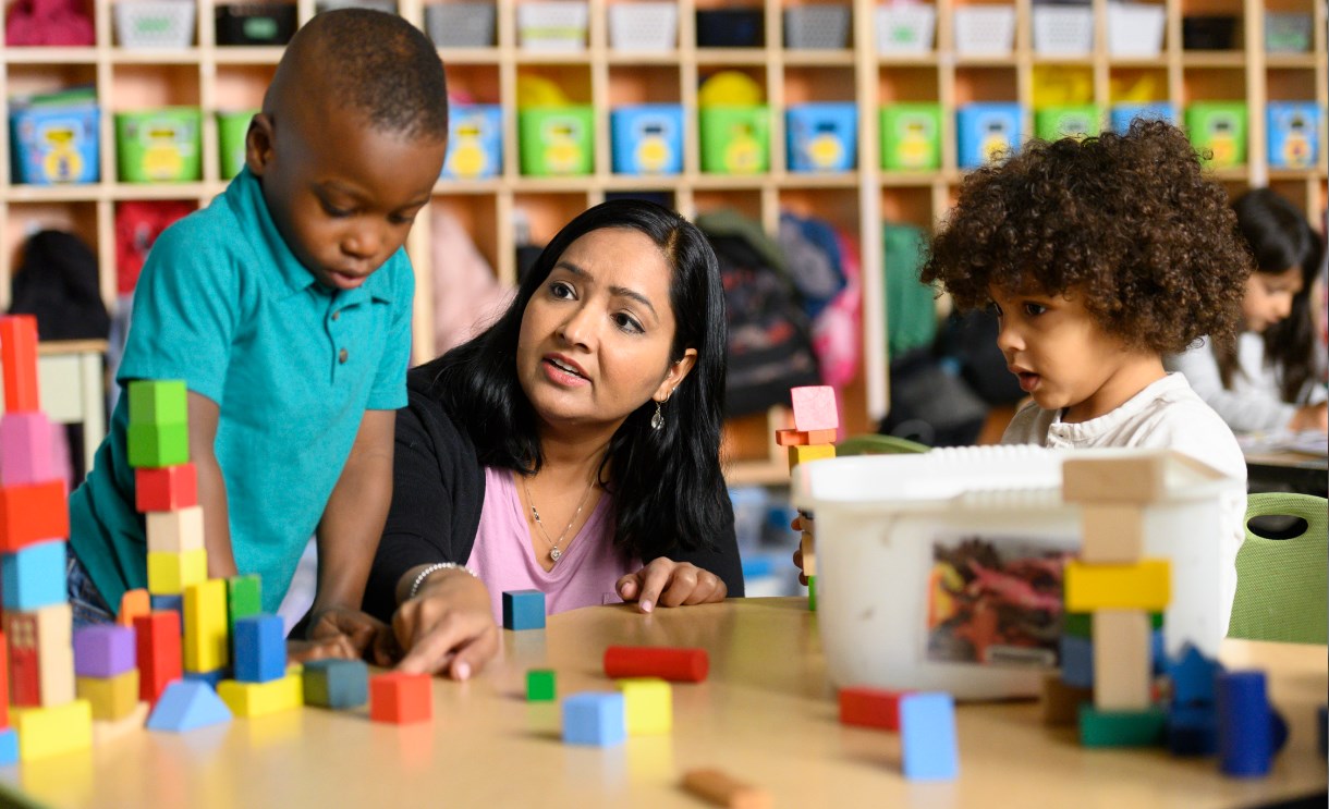 A teacher and two students in a classroom working with building blocks